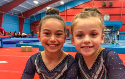 Two girls smiling at a competition in unitards.