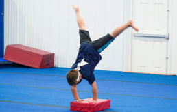 A boy doing a handstand on a mat.