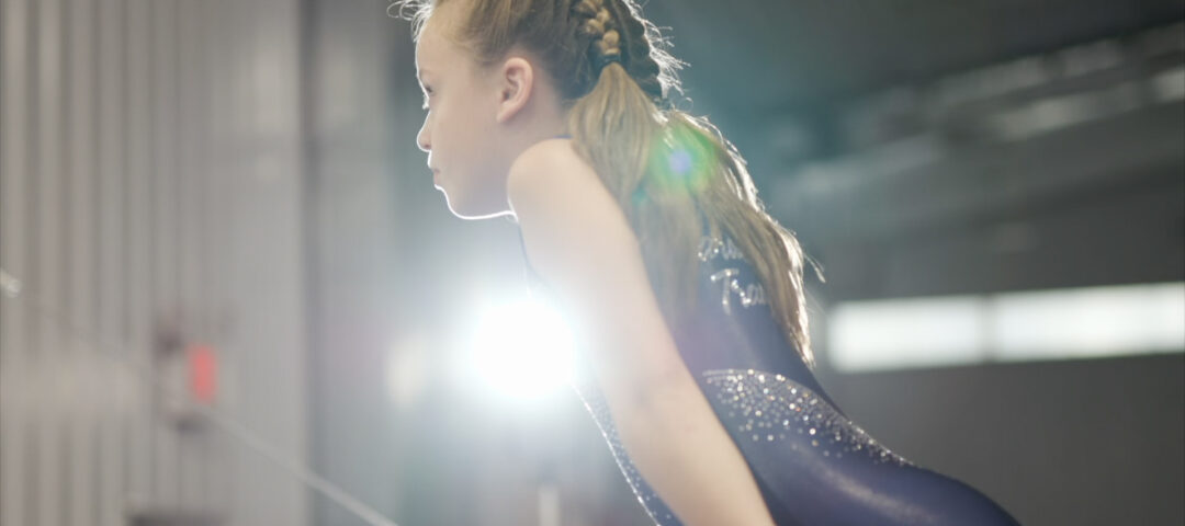 A close up of a girl on the uneven bars.