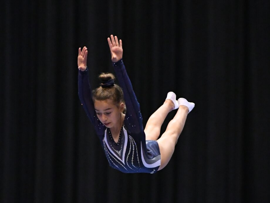 A girl keeps her posture while mid-air on trampoline.