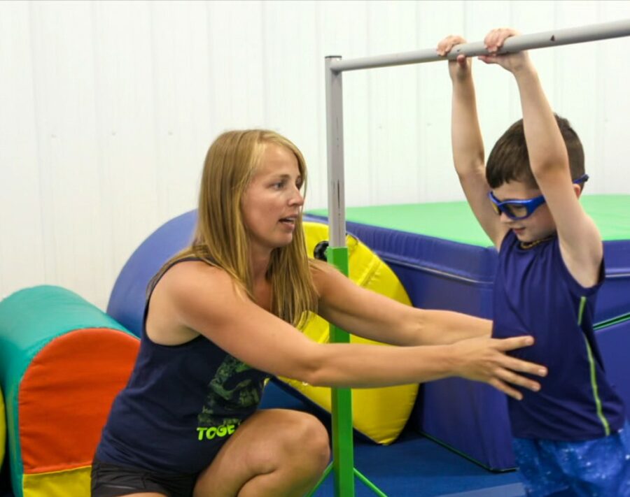 Nastia helping a boy on bars.