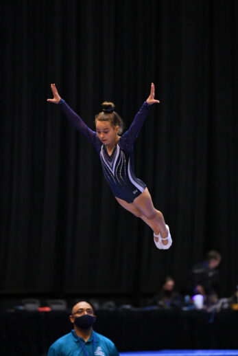 A girl jumping and keeping form at a competition.