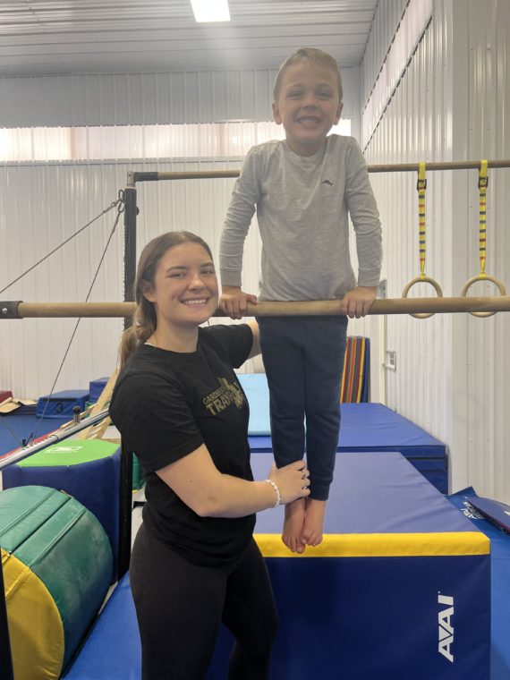 Coach Gabi working with child on the uneven bars